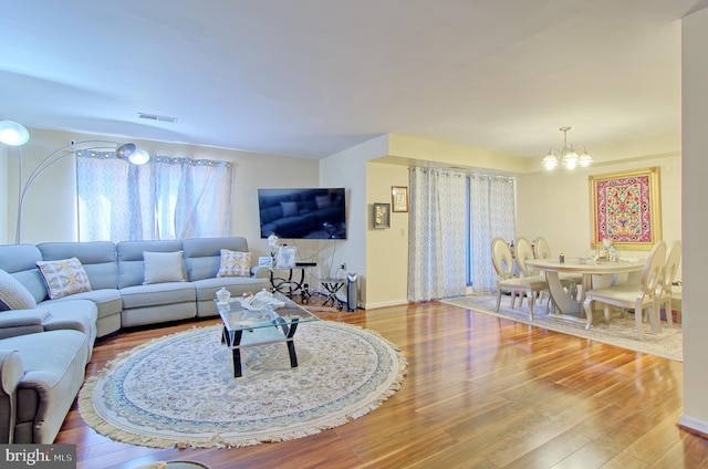 living room with light wood-type flooring, baseboards, visible vents, and a chandelier