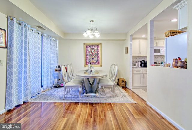 dining area featuring light wood-style floors, a chandelier, and baseboards