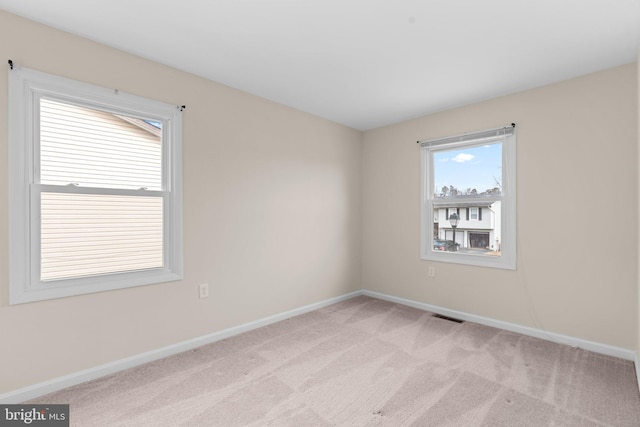 empty room with light colored carpet, visible vents, and baseboards