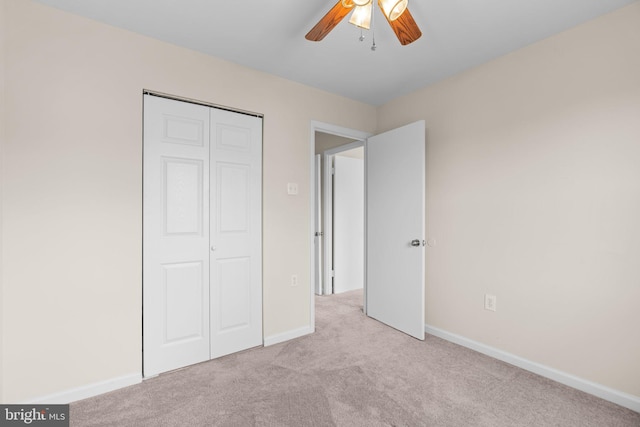 unfurnished bedroom featuring a closet, light colored carpet, ceiling fan, and baseboards