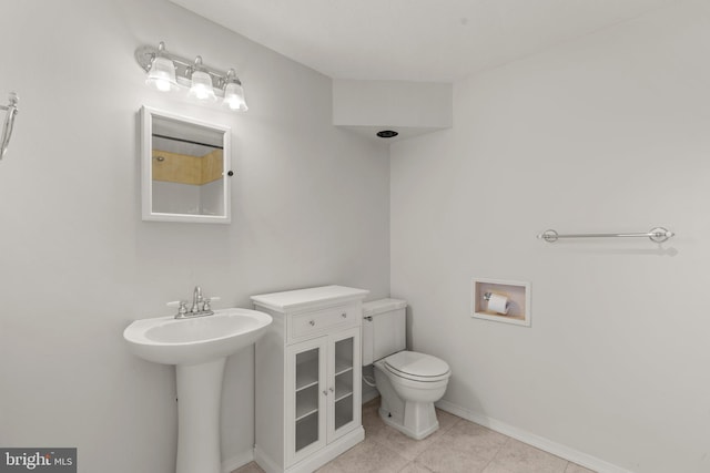 bathroom with toilet, baseboards, and tile patterned floors