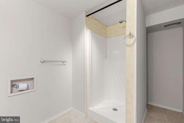 full bath featuring a stall shower, tile patterned flooring, and baseboards