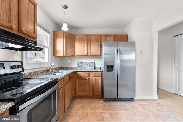 kitchen featuring appliances with stainless steel finishes, light stone counters, decorative light fixtures, under cabinet range hood, and a sink