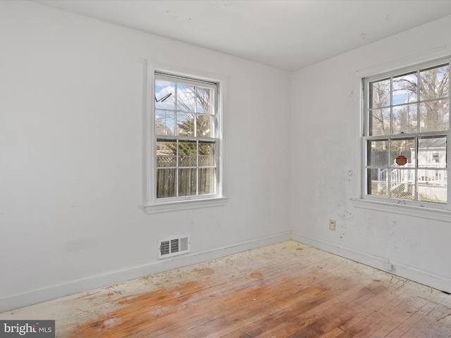 unfurnished room with light wood finished floors, visible vents, and baseboards