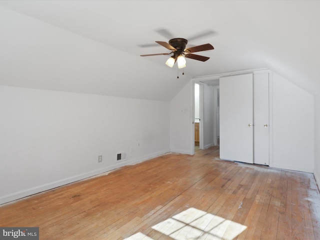 additional living space with visible vents, light wood-style flooring, a ceiling fan, vaulted ceiling, and baseboards