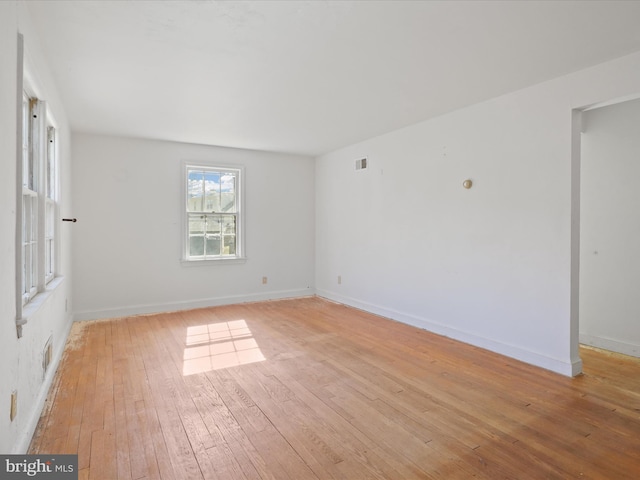 empty room featuring baseboards, visible vents, and light wood finished floors