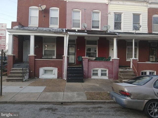 townhome / multi-family property with covered porch and brick siding