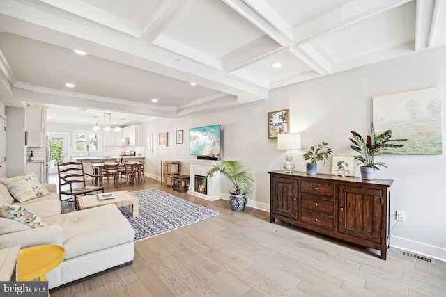 living room featuring light wood-type flooring, beam ceiling, visible vents, and baseboards