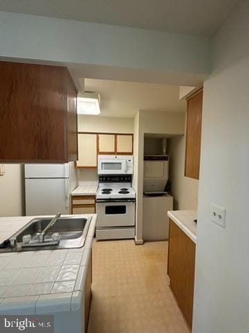 kitchen with white appliances, a sink, tile counters, brown cabinets, and light floors