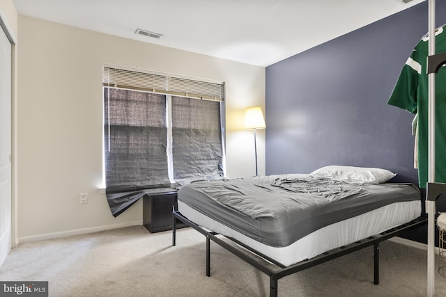 bedroom featuring visible vents, light carpet, and baseboards