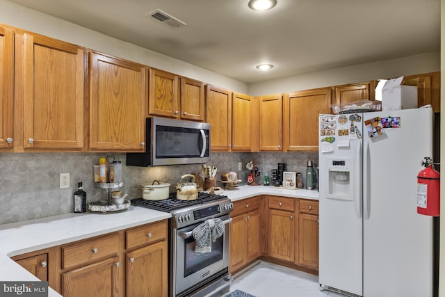 kitchen featuring backsplash, visible vents, stainless steel appliances, and light countertops