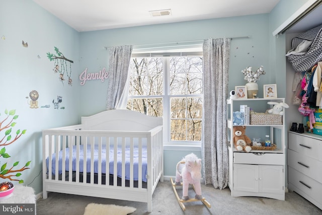 bedroom featuring a nursery area, baseboards, visible vents, and light colored carpet