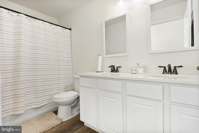 bathroom with toilet, double vanity, a sink, and wood finished floors