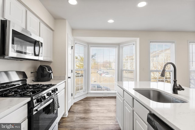 kitchen with appliances with stainless steel finishes, recessed lighting, dark wood-type flooring, and a sink