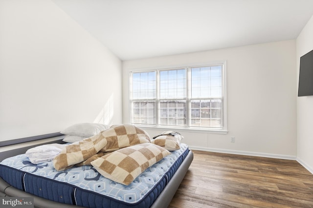 bedroom featuring baseboards, vaulted ceiling, and wood finished floors