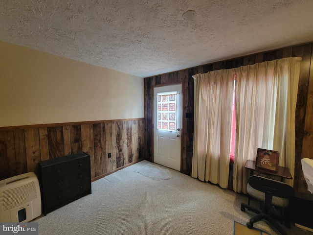 office space with light colored carpet, wainscoting, wood walls, and a textured ceiling