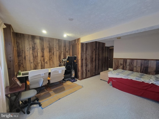 bedroom with a wainscoted wall, light carpet, wood walls, and a textured ceiling