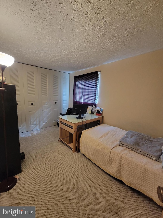 bedroom with a textured ceiling and light colored carpet