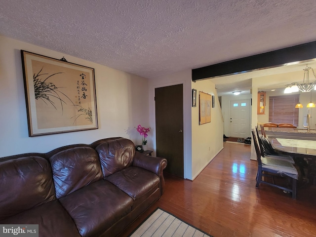 living room with a textured ceiling, baseboards, and wood finished floors