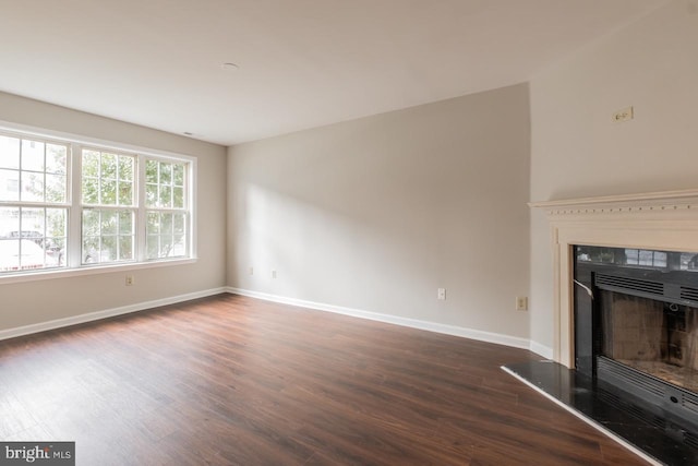 unfurnished living room featuring a fireplace, baseboards, and dark wood-type flooring