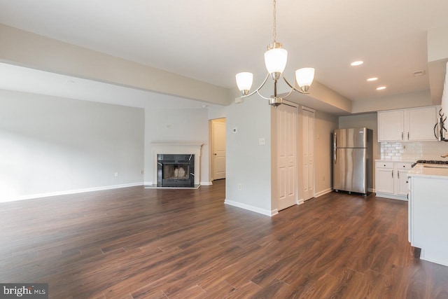 kitchen with white cabinetry, open floor plan, light countertops, appliances with stainless steel finishes, and dark wood-style floors