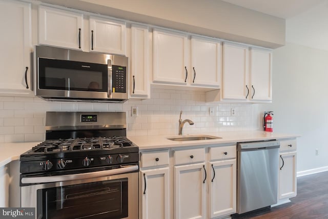 kitchen with light countertops, appliances with stainless steel finishes, a sink, and white cabinets