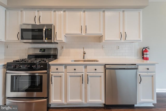 kitchen featuring stainless steel appliances, white cabinets, light countertops, and a sink