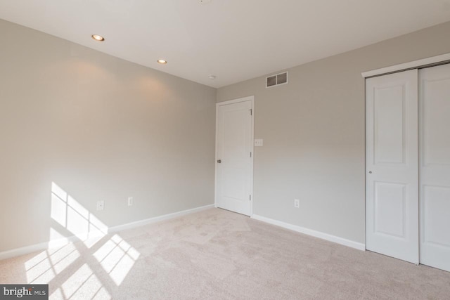 unfurnished bedroom featuring light carpet, a closet, visible vents, and baseboards