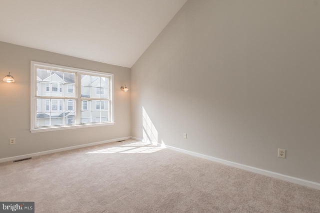 empty room featuring vaulted ceiling, carpet flooring, visible vents, and baseboards