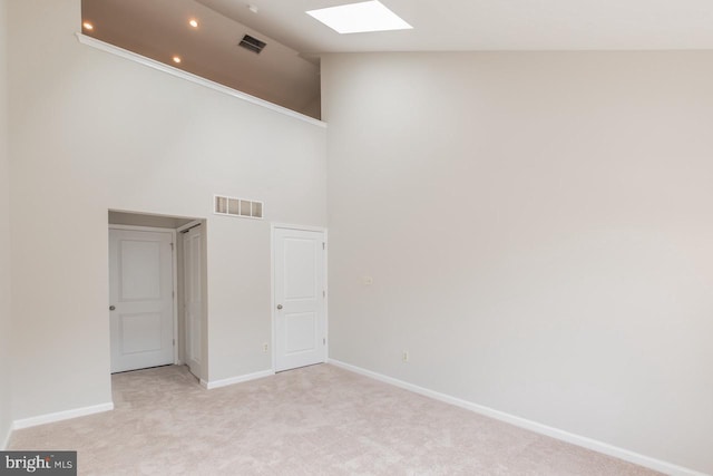 unfurnished room featuring light colored carpet, visible vents, baseboards, and a skylight