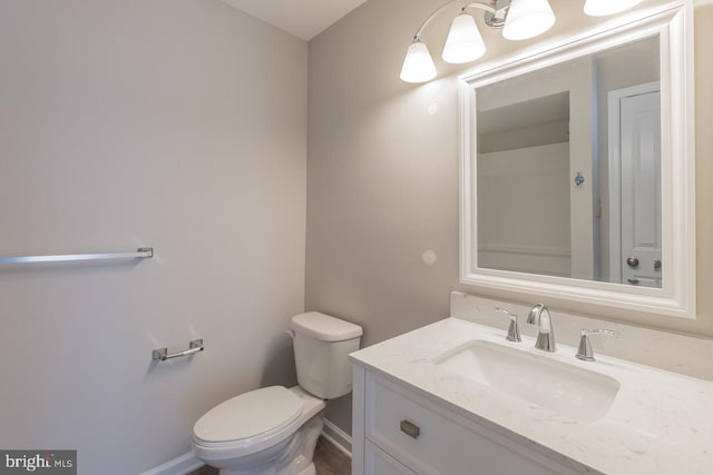 bathroom with toilet, vanity, and baseboards