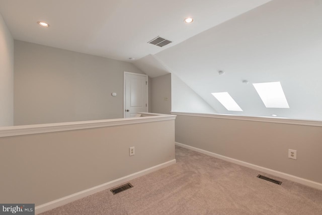 additional living space with baseboards, visible vents, and vaulted ceiling