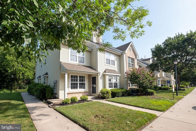 view of front facade with brick siding and a front yard