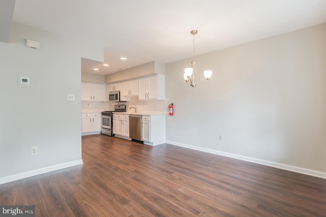 kitchen featuring baseboards, dark wood finished floors, appliances with stainless steel finishes, light countertops, and white cabinetry