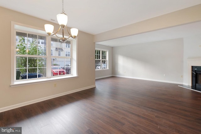 interior space with dark wood-type flooring, a healthy amount of sunlight, and a fireplace with raised hearth