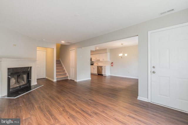 unfurnished living room featuring baseboards, visible vents, a fireplace with raised hearth, stairway, and dark wood-style flooring