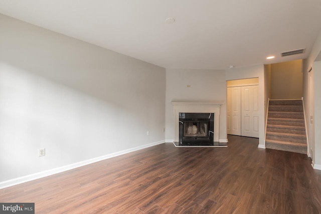 unfurnished living room featuring stairway, dark wood finished floors, visible vents, and baseboards