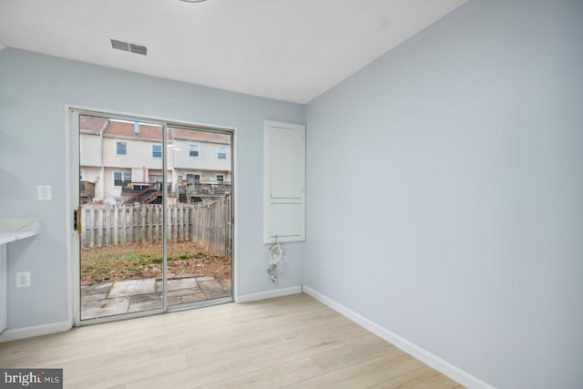 empty room with wood finished floors, visible vents, and baseboards