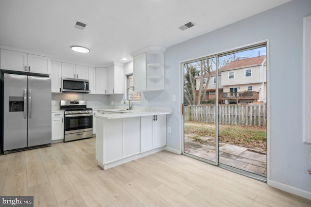 kitchen with stainless steel appliances, visible vents, a peninsula, and open shelves