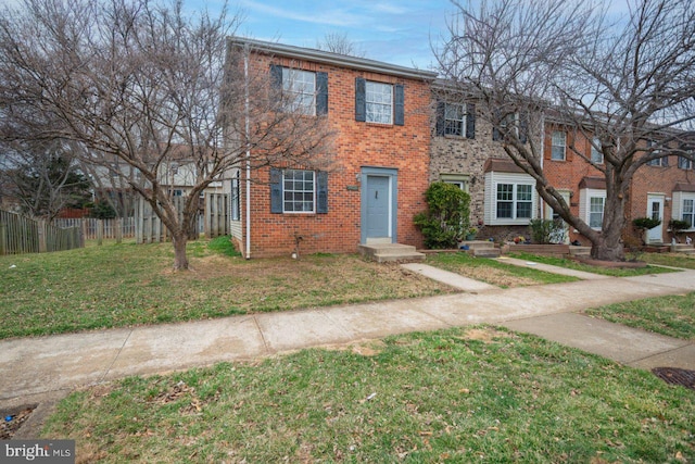 view of front of house featuring fence, a front lawn, and brick siding