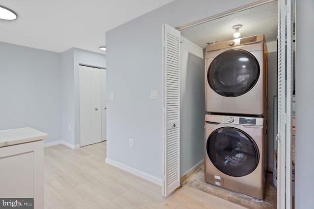 laundry room with laundry area, light wood-style flooring, baseboards, and stacked washer / drying machine