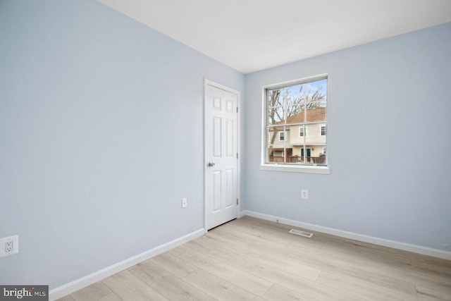 unfurnished room featuring light wood-style flooring, visible vents, and baseboards