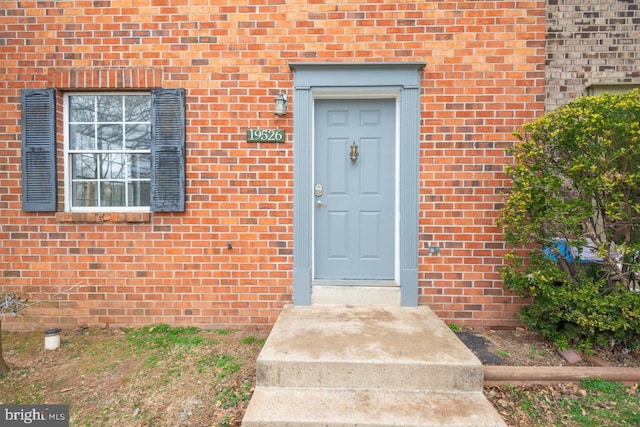 view of exterior entry featuring brick siding