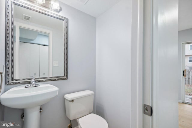 bathroom with toilet, wood finished floors, and visible vents