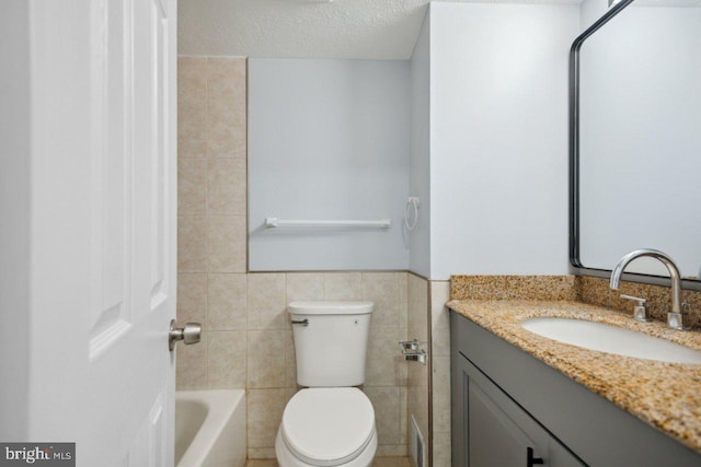 full bath featuring a washtub, tile walls, toilet, a textured ceiling, and vanity