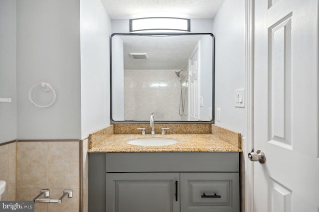 bathroom featuring a textured ceiling, toilet, visible vents, vanity, and a shower