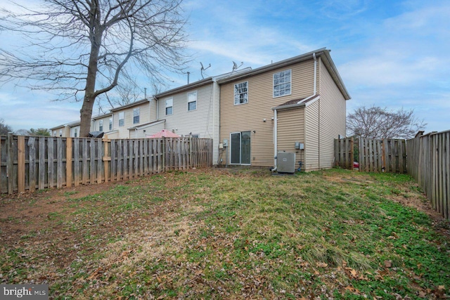 back of house with a fenced backyard, a yard, and central AC unit