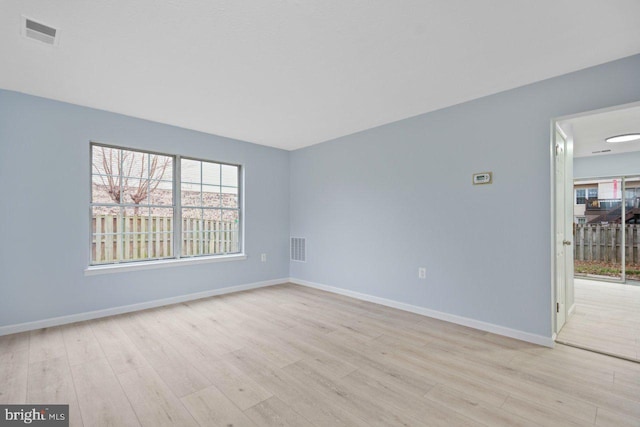 empty room featuring baseboards, visible vents, and light wood finished floors