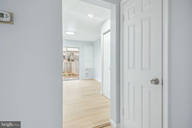 hall featuring light wood-style flooring and baseboards