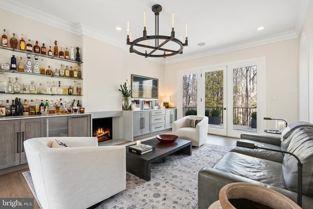 living area featuring an inviting chandelier, crown molding, a dry bar, and light wood finished floors